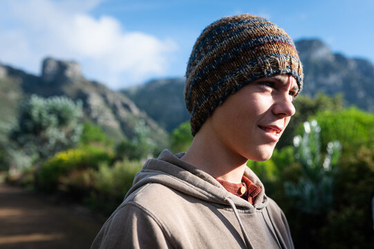 Young person stands outdoors in a green landscape with mountains