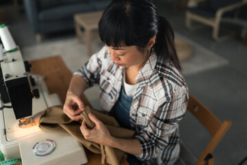 Woman sewing fabric using sewing machine at home