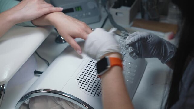 Technician selects suitable nail tips by natural nail width for upcoming nail extension
