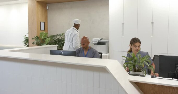 African American reception staff, clinician checking monitor walking to printer getting reports