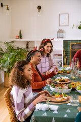 Naklejka premium African american family sharing holiday meal in dining room with roast poultry, antler headbands