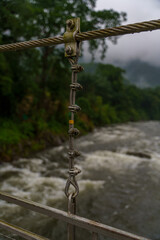Obraz premium Chain hangs over a river, with a few of the links hanging over the water