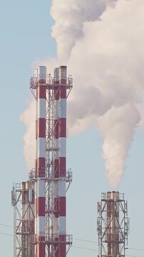 Thermal power plant pipes with vapor rising to the sky. Vapor rising in front of the blue sunny sky.