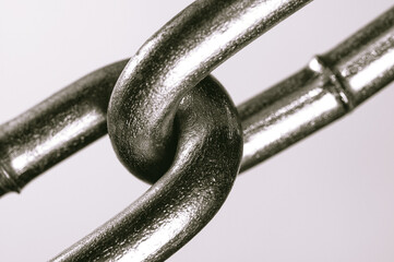 Two linked links of one chain close-up, black and white.