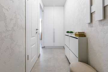 Modern minimalist entryway with white wardrobe and shoe cabinet