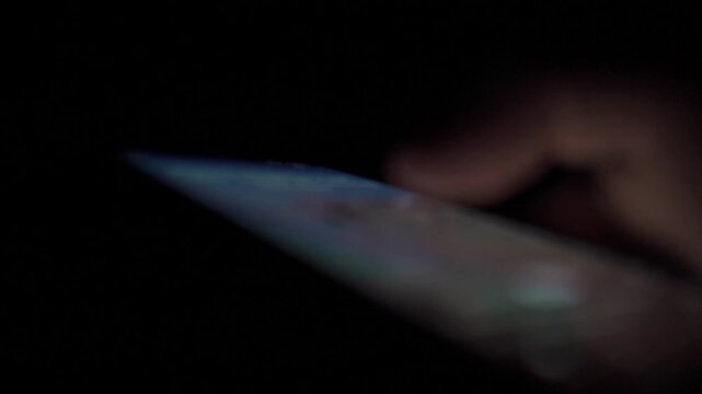 Man Scrolling Social Media on Smartphone at Night