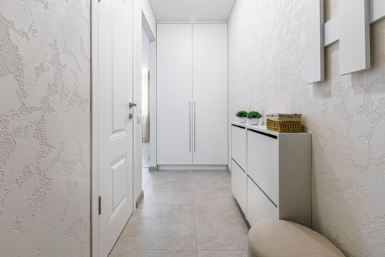 Modern minimalist entryway with white wardrobe and shoe cabinet