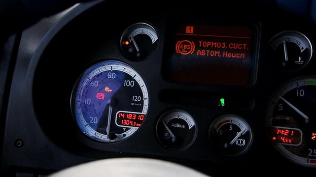Truck dashboard interior. Illuminated gauges: speedometer, fuel, temperature, AdBlue. Digital display: mileage, time, external temperature Orange warning brake system malfunction
