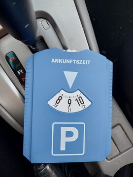 European blue parking disc displaying arrival time inside a car. Concept of parking regulation, time control, urban transport rules, and everyday driving in Germany and European cities.