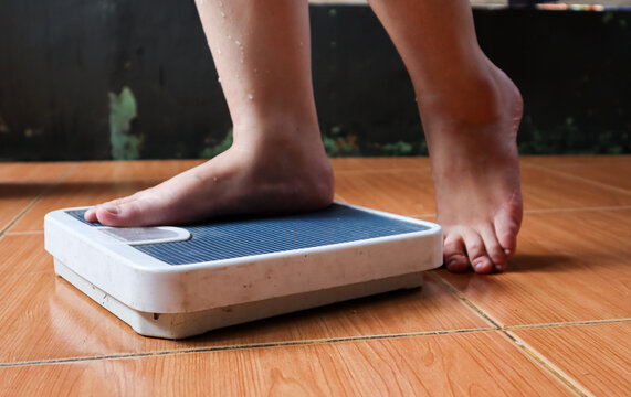 Close up of bare feet stepping onto a bathroom weighing scale on tiled floor at home, representing weight measurement, daily routine, personal health monitoring, and indoor lifestyle.