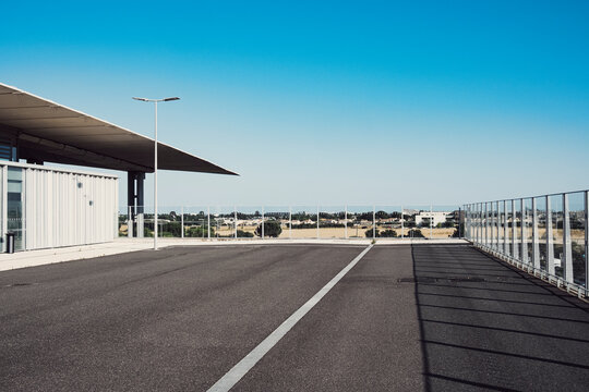 Modern urban architecture empty roadway with fence canopy and sky where lines guide perspective creating clean infrastructure background wide view