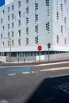 Modern urban architecture empty intersection street with building facade and clear sign as sharp shadow cuts across asphalt in daylight