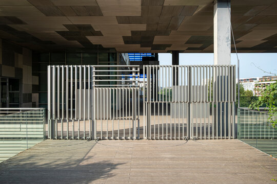 Modern urban architecture empty concrete underpass with security gate entrance creating dramatic shadow in bright daylight wide view