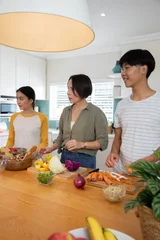 Selbstklebende Fototapeten Zu Kochen Diverse family preparing vegetables on island counter in home kitchen with mixing bowls  © wavebreak3