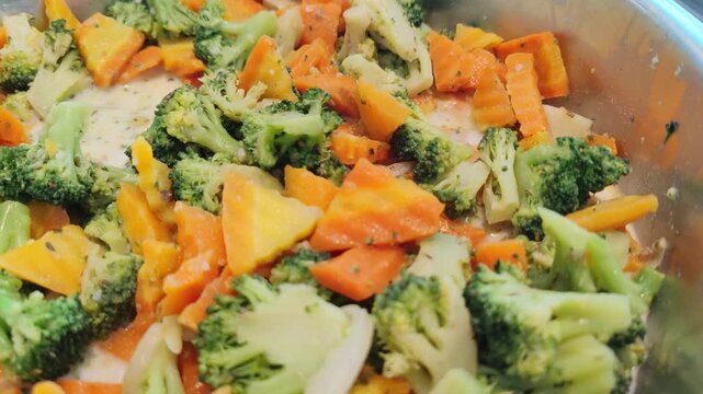 Close-up video of mixed vegetables including broccoli, carrots, and potatoes cooked in a light creamy sauce. The colorful vegetables appear fresh and healthy, served in a buffet tray. Suitable for the