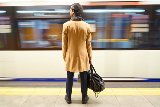 Man waiting on subway platform as train passing by