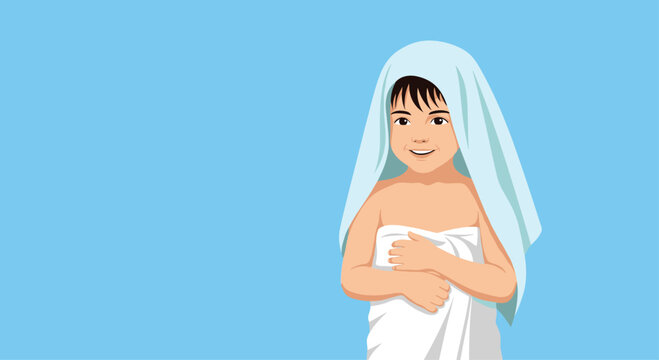 Happy young boy smiling and holding a white towel around his chest with another light blue towel draped over his head.