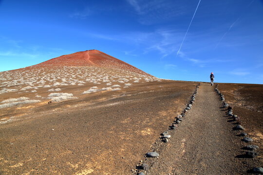 The ascent of the colorful volcano Montana Bermeja  in La Graciosa, Lanzarote, Canary Islands, Spain, with a hiking path in the foreground leading to the top of the mountain