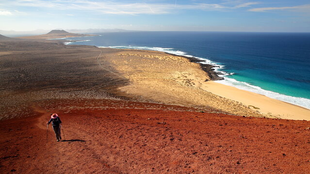 View from the top of the colorful volcano Montana Bermeja towards the island La Graciosa, Lanzarote, Canary Islands, Spain, with the sandy beach Playa de las Conchas on the right 