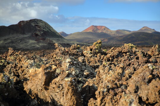 Close-up on lava rocks in Lanzarote, Canary Islands, Spain, with the Timanfaya volcanoes in the background. Picture taken from the hiking path around Caldera Colorada