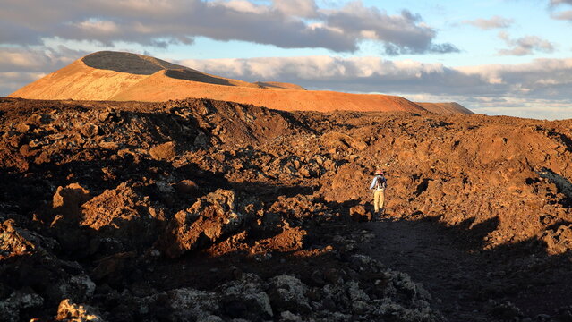 Lunar landscape at sunrise with the popular Caldera Blanca hike  in Lanzarote, Canary Islands, Spain, with lava rocks in the foreground