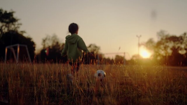 Young child staring at a soccer goal at sunset with ball nearby. Symbolizes dreams, ambition, and the journey to becoming a World Cup player.