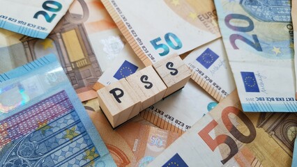 PSS acronym made of wooden letter cubes on pile of Euro banknotes. Plano de Seguran&ccedil;a Social (Social Security Plan)