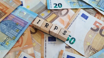 IRPS acronym made of wooden letter cubes on pile of Euro banknotes.  Imposto sobre os Rendimentos das Pessoas Singulares (Personal Income Tax)