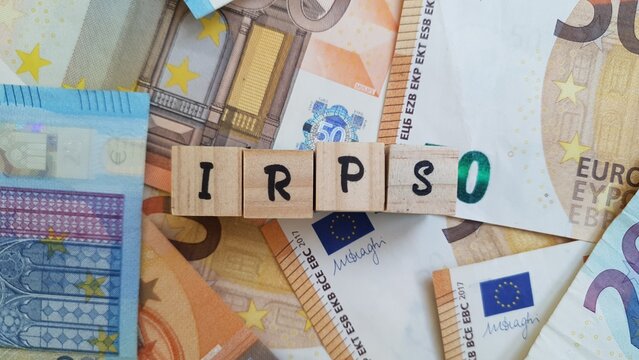IRPS acronym made of wooden letter cubes on pile of Euro banknotes.  Imposto sobre os Rendimentos das Pessoas Singulares (Personal Income Tax)