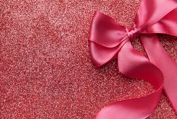 Fototapeta premium Pink ribbon bow on sparkling glitter background