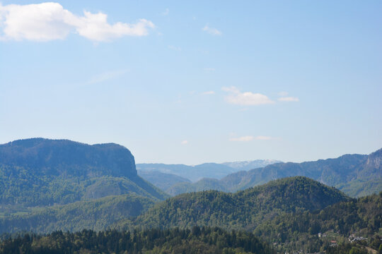 A panoramic mountain view from the Podhom circular trail showing the distinctive Babji zob peak and the Jelovica plateau above the green valleys and Zasip village in Slovenia