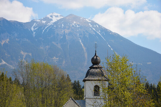 A panoramic mountain view from the Podhom circular trail showing the distinctive Babji zob peak and the Jelovica plateau above the green valleys and Zasip village in Slovenia