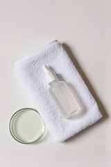 Fototapeta premium Glass dropper bottle on white towel with petri dish for cosmetic research