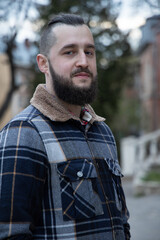 bearded millennial middle adult man portrait calm facial expression vertical photography outdoor blurred background view