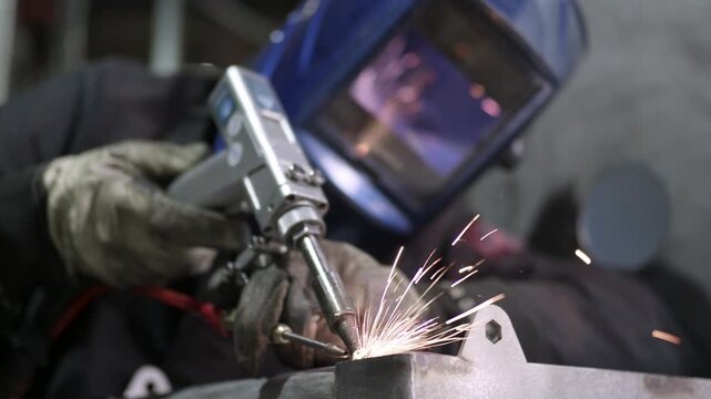 Welder performing manual laser welding with sparks in workshop