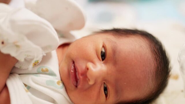 Close-up of a smiling newborn baby lying down, with bright eyes and a gentle expression. Perfect image for concepts related to infant happiness, family love, and baby care.