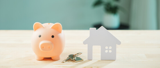 Real estate investment money piggy bank saving home house property insurance, pink piggy bank beside white house model with keys represents plan to save for future mortgage