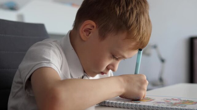 Young school-age boy does his homework and does his homework.