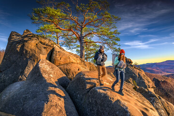 Two hikers walking along rocky mountain ridge at golden hour, outdoor exploration