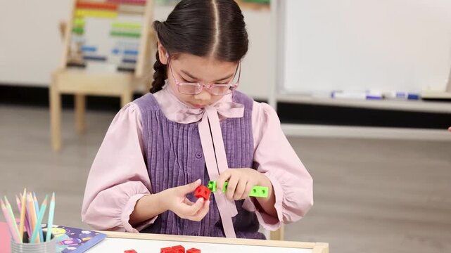 Young Girl Sorting and Connecting Colorful Math Manipulative Blocks in Classroom