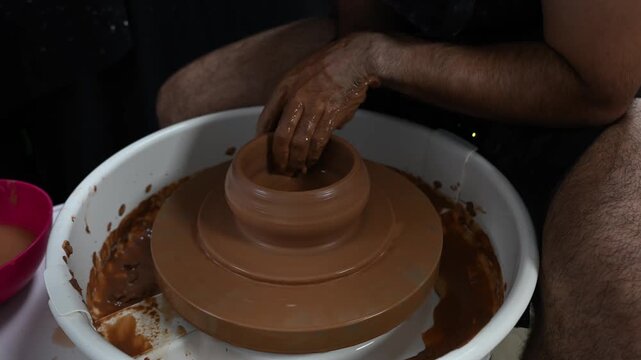 Male potter using a pottery wheel to demonstrate the basic pulling up technique to form a clay cylinder, traditional ceramic craftsmanship.