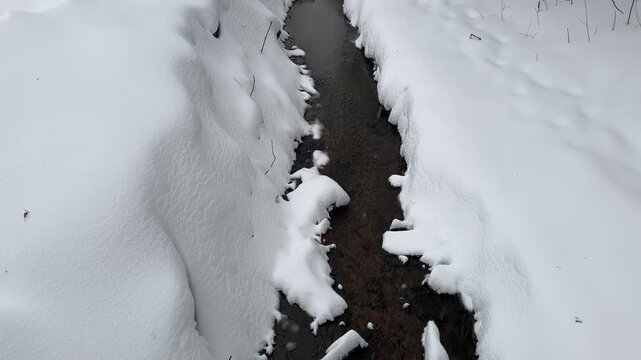 Winter creek surrounded by large snowdrifts