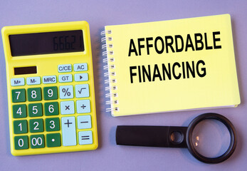 AFFORDABLE FINANCING - words in a notebook with a calculator and magnifying glass in the background