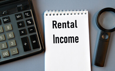 RENTAL INCOME - words in a notebook with a calculator and magnifying glass in the background