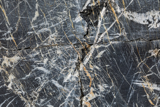 vista macro di una superficie lavorata e liscia di marmo nero naturale, con sfumature di colore e venature bianche