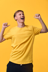 Energetic man celebrating in a bright yellow shirt, arms raised in joy and triumph, conveying excitement, happiness, and a festive, upbeat mood in a clean studio setting © SHOTPRIME STUDIO