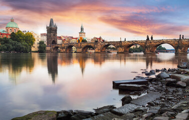Evening view of illuminated bridges over Vltava River in Prague, Czech Republic, with historic towers, city lights, and reflections creating romantic atmosphere.