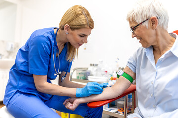Professional nurse in blue scrubs taking a blood sample from the arm of a senior woman patient using a needle and syringe during a medical checkup in a bright clinical laboratory setting