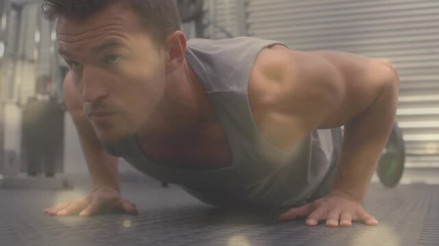 Animation of light spots over caucasian man exercising at gym