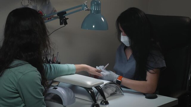 Correcting nail shape with file during salon procedure for hand and nail care

